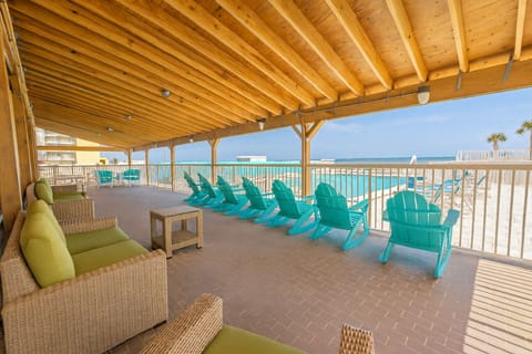 Unwind in the shaded lounge area overlooking the beach, complete with colorful chairs that enhance your coastal getaway.