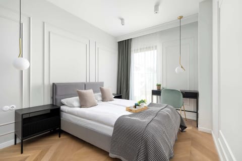 Elegant bedroom with upholstered headboard, soft textiles, and classic wall mouldings.