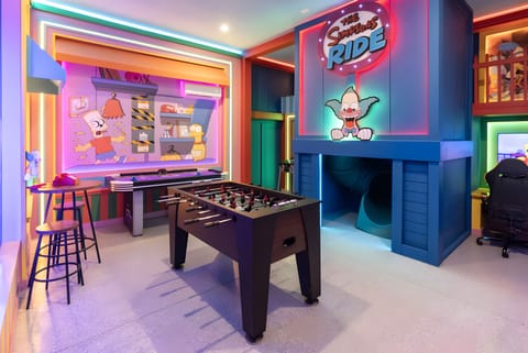 Discover a lively game room bursting with color and energy, featuring a foosball table and a cozy gaming nook. With illuminated walls and whimsical art, it's the ideal spot for enjoyable evenings with family and friends.