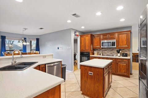 Spacious chef’s kitchen featuring warm wood cabinetry, sleek white quartz countertops, and a convenient center island for easy meal prep.