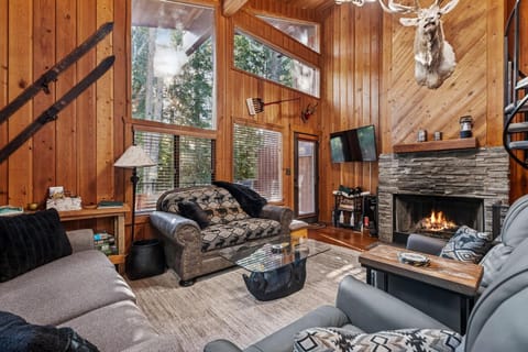 Cozy up by the crackling fireplace in this rustic living room, where warm wood walls and comfortable seating create your perfect mountain retreat.