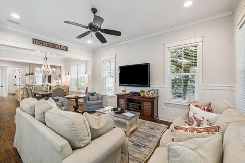 Sink into plush sofas in your bright, airy living space where coastal charm meets modern comfort with ceiling fan breezes and entertainment ready.