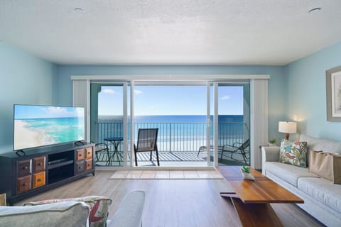 The coastal-inspired living space features comfortable seating, flat-screen TV, and floor-to-ceiling sliding doors to the beach balcony.