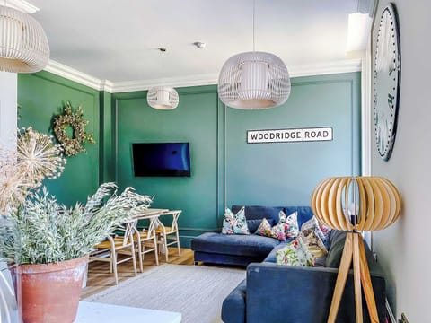Stylish and inviting living space with elegant green panelled walls, warm wood floors, and modern décor. Relax on the plush corner sofa, enjoy the wall-mounted TV, or dine in comfort. A cosy yet sophisticated setting perfect for both business and lei