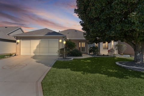Beautiful single-story home with manicured landscaping and garage, photographed during a stunning sunset in a peaceful residential neighborhood.