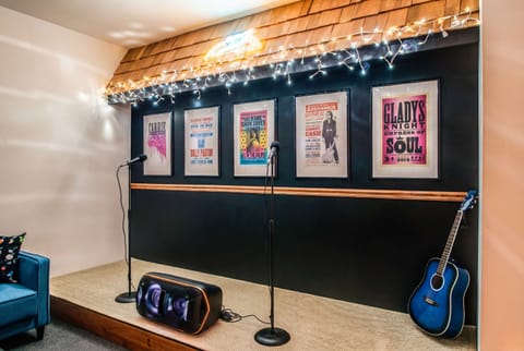 String lights frame the karaoke stage, guitar within arm's reach, posters setting the vibe for songs between rounds of drinks