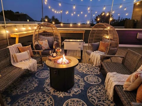 Nighttime rooftop with string lights, egg chairs, and a patterned rug, the spot to wrap up the evening together