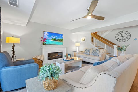 An airy, beautifully styled living space featuring comfortable seating, a cozy fireplace, and sliding doors that open to the private balcony.
