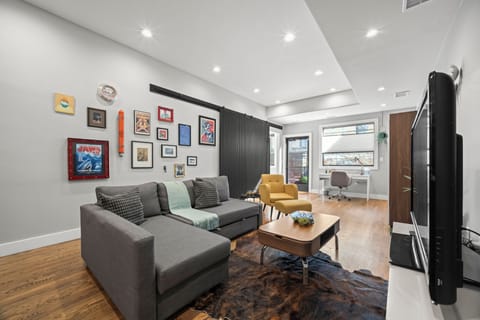 Bright, modern living space with large windows, warm floors, and a comfortable work area.