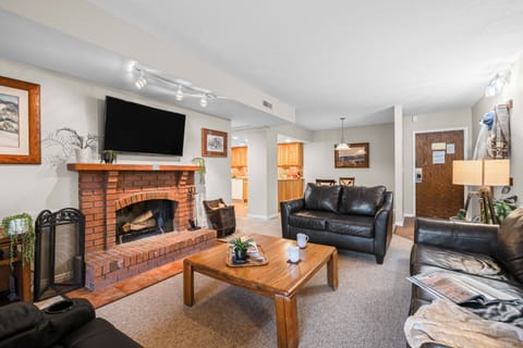 Cozy living room featuring a warm brick fireplace and leather seating, the perfect spot to unwind.