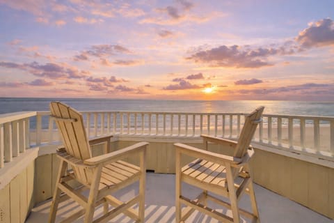 Oceanfront rooftop deck with two Adirondack chairs.
