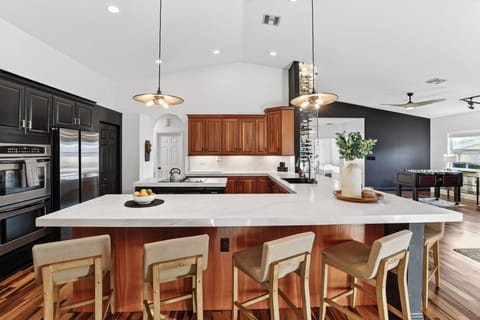 Open kitchen with oversized island, bar seating, and a stylish wine display.