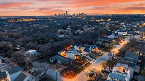 Sweeping aerial view at sunset showcasing the neighborhood and Austin skyline in the distance.