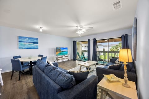 Relax in your spacious living area with plush navy seating, dining space, and private balcony access for the perfect getaway.