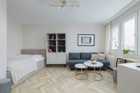 A combined bedroom and sitting area with a bed, sofa, and small coffee table. The neutral tones and simple furniture create a calm, minimalist atmosphere.