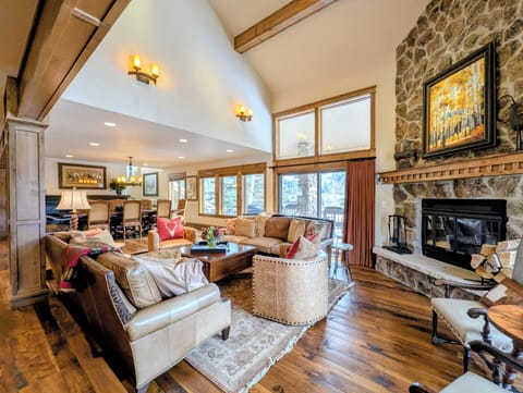 Gather around the stone fireplace with loved ones in this warm living space featuring soaring ceilings and mountain views.