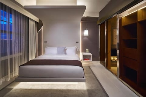 Unwind in a sleek king bed with soft, ambient lighting.