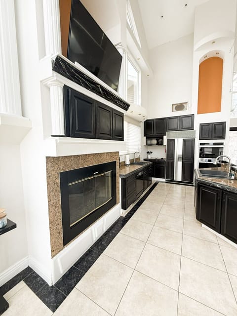 Gourmet kitchen with sleek black cabinetry, granite countertops, fireplace, and high ceilings for a luxury lakefront experience.