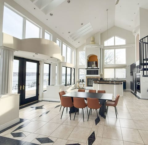 Elegant lakeview kitchen and dining area featuring soaring ceilings, modern design, and panoramic waterfront windows.