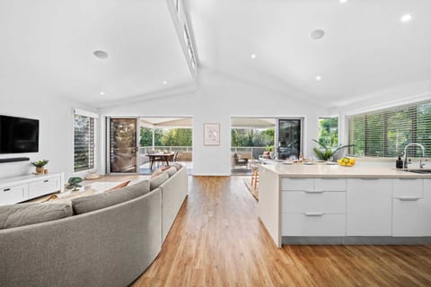 A bright and modern living room with a large L shaped sofa and pastel accents.