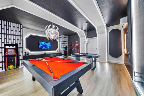 Discover our lively game room with elegant black pool tables and cheerful red felt, ideal for friendly matches. The chic pendant lighting enhances the modern vibe, and the unique wall decor adds a fun touch for everyone to enjoy.