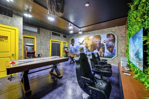 Experience a lively game room with a sleek air hockey table and cozy chairs, ideal for fun competitions or relaxation. Enjoy playful wall art and refreshing greenery that enhance the inviting atmosphere.