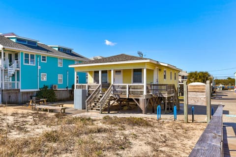 Charming coastal cottages with vibrant turquoise and sunny yellow exteriors, featuring elevated porches and boardwalk access.