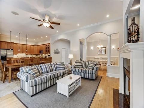 Comfortable living room features striped sofas, a ceiling fan, and an open layout ideal for group gatherings.