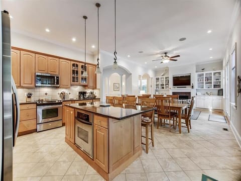Open-concept kitchen features warm wood cabinetry, a large center island, and stainless steel appliances ideal for group cooking.