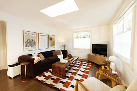 Sun-filled living room featuring a skylight, cozy sectional, and stylish mid-century furnishings—perfect for relaxing and gathering together