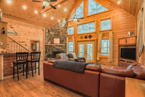 Great room with loft staircase — antler chandelier, fireplace, and French doors