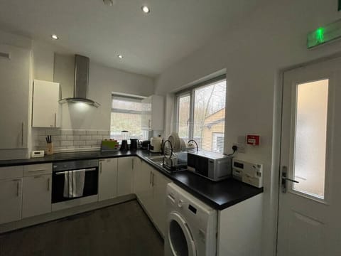 A wider kitchen view showing the oven, hob, washing machine, and rear door.