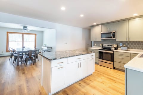 Kitchen - Kitchen; hallway at the right leads to the living room. Second dining room overlooking the front yard is shown at left. Off to the left is the hallway to the attached apartment, laundry, and half bathroom.