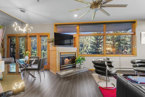 Settle into your bright, modern living space where floor-to-ceiling windows frame stunning forest and mountain scenery. Gather by the cozy fireplace or step out onto your private deck to soak in the alpine views.