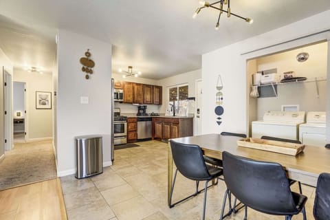 The modern dining area comfortably seats six and flows directly into the updated kitchen featuring stainless steel appliances. A full-size laundry suite is discreetly tucked behind floor-to-ceiling curtains for easy guest access.