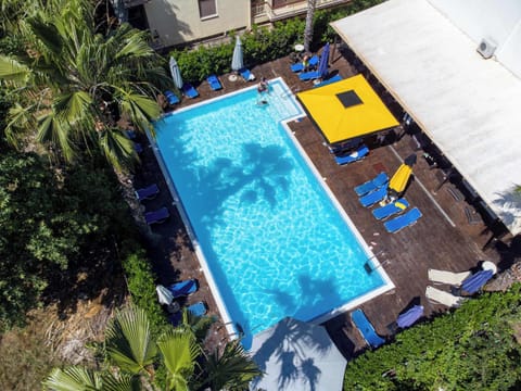 Spacious pool area with sunbeds and greenery, perfect for enjoying the sunshine, taking a refreshing swim, or simply embracing the relaxed pace of a Greek holiday.