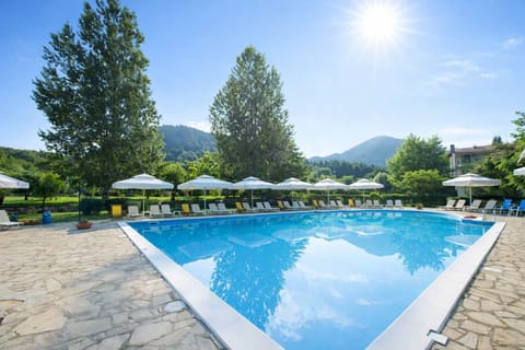 Large Outdoor Swimming Pool Surrounded by Greenery, Sunbeds, and Peaceful Mountain Views