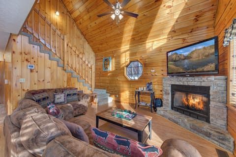 Curl up in your cozy mountain living room, where crackling fireplace warmth meets rustic cabin charm and comfortable seating awaits your relaxation.