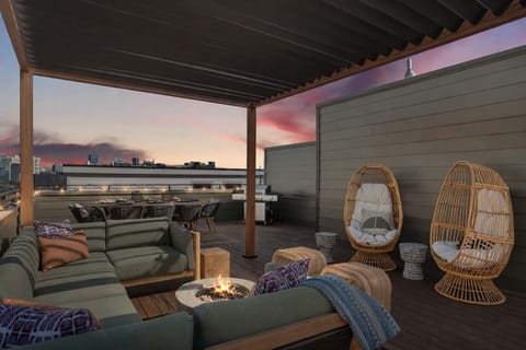 Golden hour rooftop with pergola lounge, firepit, and skyline-view dining.
