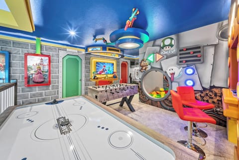 Enter a lively game room adorned with colorful murals and a sleek air hockey table for endless fun. The playful blue ceiling and whimsical decor craft an energetic atmosphere perfect for guests of all ages to enjoy.