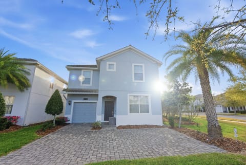 Experience the charm of this coastal blue home, featuring a spacious front driveway framed by lush palm trees. The warm sunlight shines on the inviting façade, hinting at a pleasant ambiance that awaits you inside.