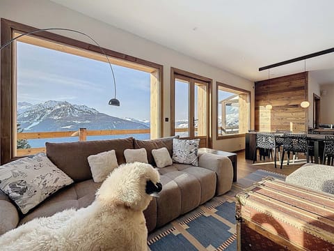 Elegant alpine living room at Chalet Shangri-La, fully renovated in 2025, featuring warm wood accents, plush seating, and breathtaking valley views from L’Orée.