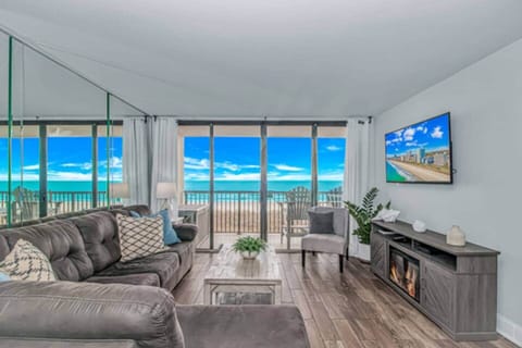Oceanfront living room with floor-to-ceiling views & private balcony.