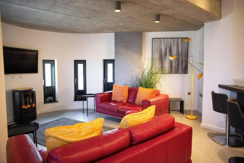 Living area with sofas, log burner, curved wall with long windows