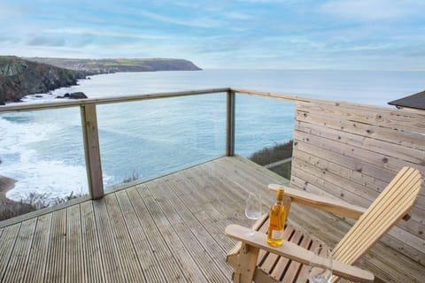 Seaside view from wooden deck with chair and bottle on armrest