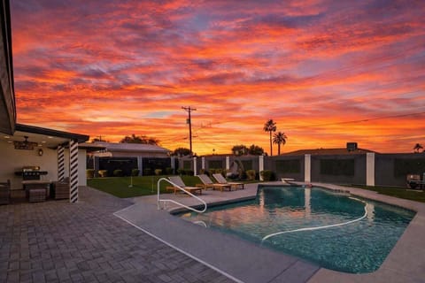Private backyard featuring a sparkling pool, sun loungers, mini golf, and a covered patio with outdoor seating, and a BBQ grill.