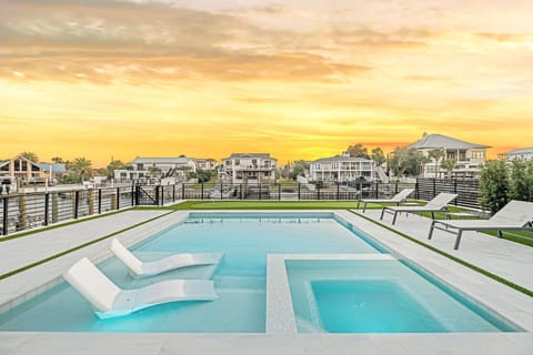 Modern pool area with built-in loungers and hot tub overlooking waterfront neighborhood at golden hour.