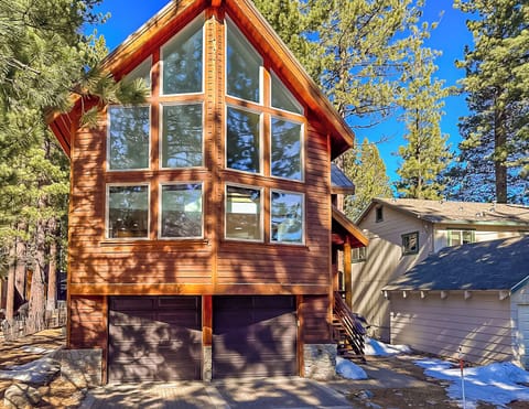 Modern mountain cabin featuring stunning floor-to-ceiling windows and rich cedar siding nestled among towering pines.
