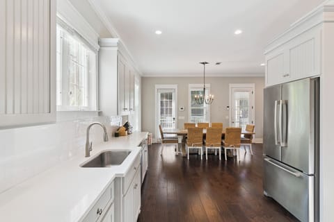 Your gourmet kitchen flows seamlessly into the dining area, where pristine white cabinets and gleaming counters invite culinary adventures.