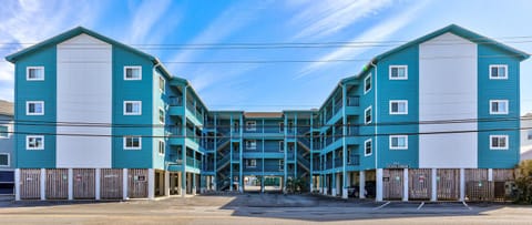 Vibrant beachfront property featuring distinctive turquoise and white architecture with convenient ground-level parking.